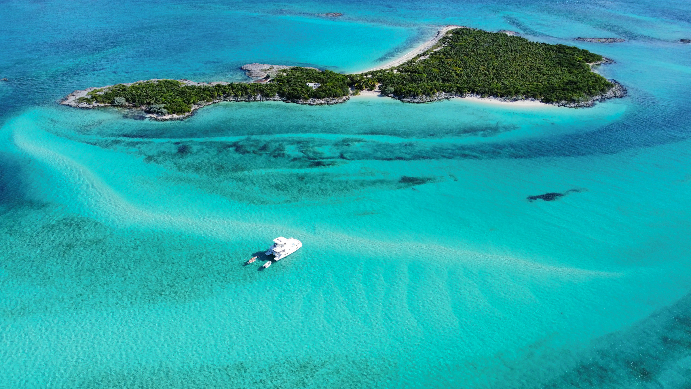 Catamaran anchored in crystal-clear turquoise waters near tropical island in the Bahamas